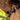 Person wearing a high-visibility vest and gloves holding a angle tool in an indoor setting with tools and equipment in the background.