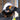 Person wearing a white hard hat and black gloves with orange accents, standing in front of a window.