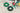 Two green circular plastic spool covers, one green and one black with green accents, shown on a concrete floor next to a green spool stand holding red, white, and yellow wire.