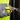 Person wearing a high-visibility safety vest and gloves holding pliers with a dark background