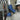 Person wearing a hard hat and blue gloves working on electrical panel with multimeter